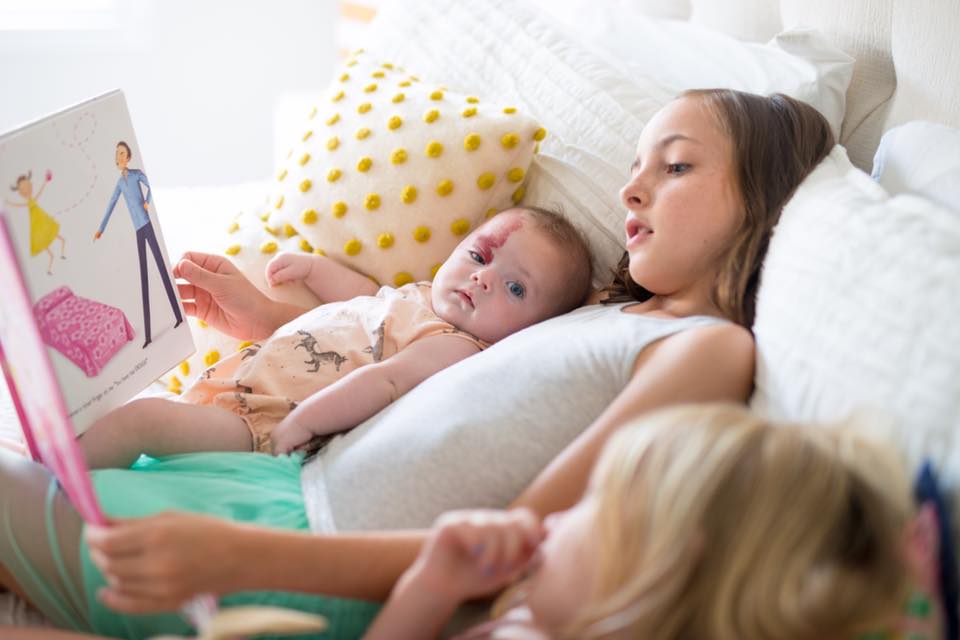 Photo of sisters reading a book together