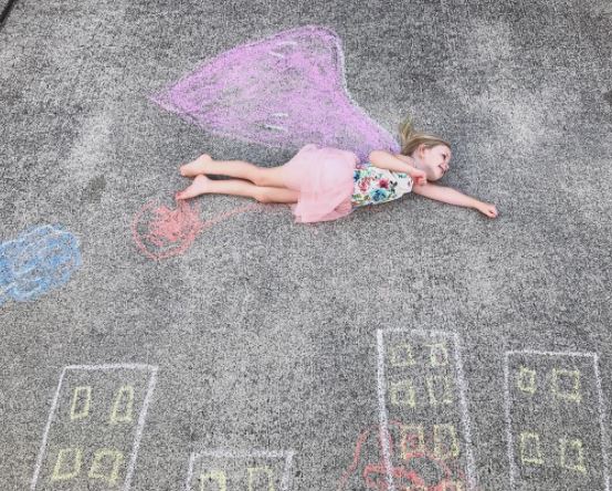 Sidewalk chalk art with toddler flying over skyscrapers