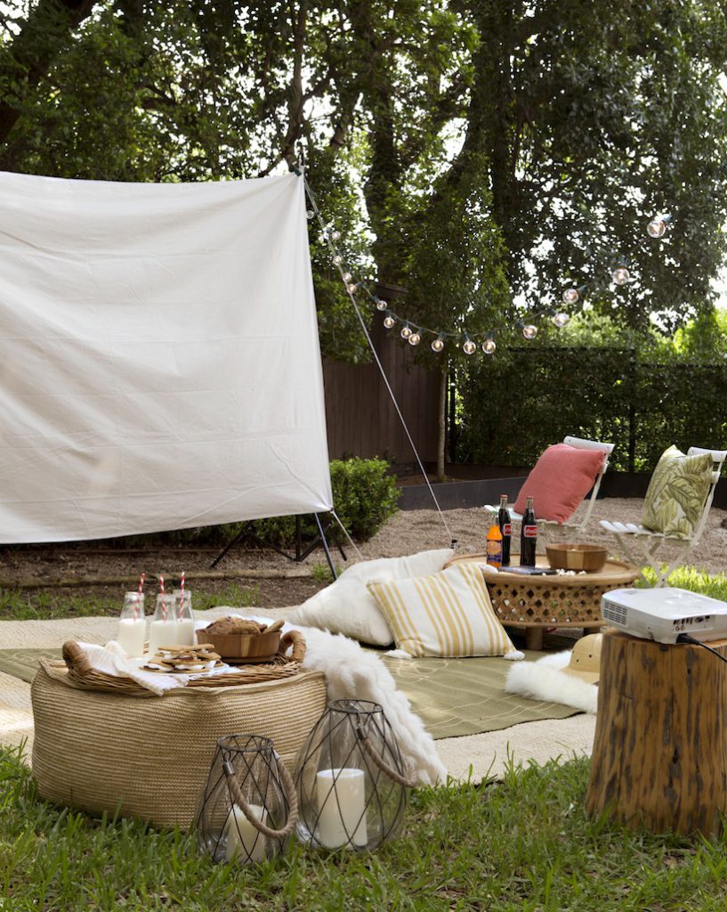 Backyard movie screening set up with string lights and rugs